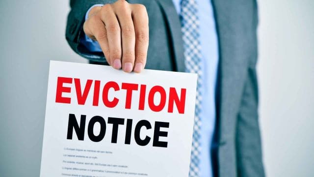 person-in-a-business-suit-holding-up-a-paper-with-the-word-eviction-notice