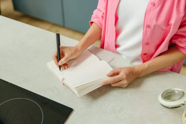 person Writing on Notebook