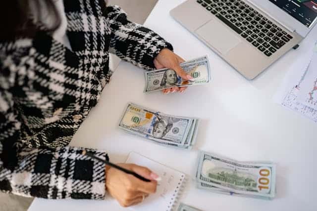 person counting money with notebook and pen