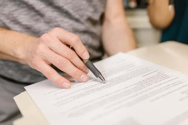 hand holding pen on white paper